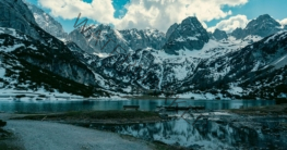 Bergsee zwischen Felswänden mit Wanderweg am Ufer